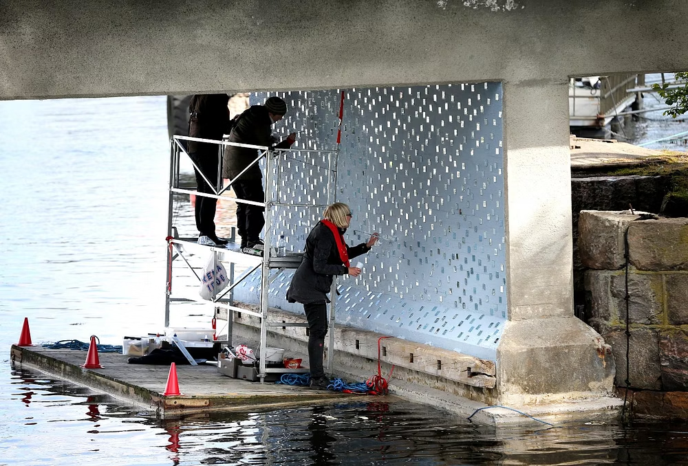 Anna and team installing mirror tiles under the bridge